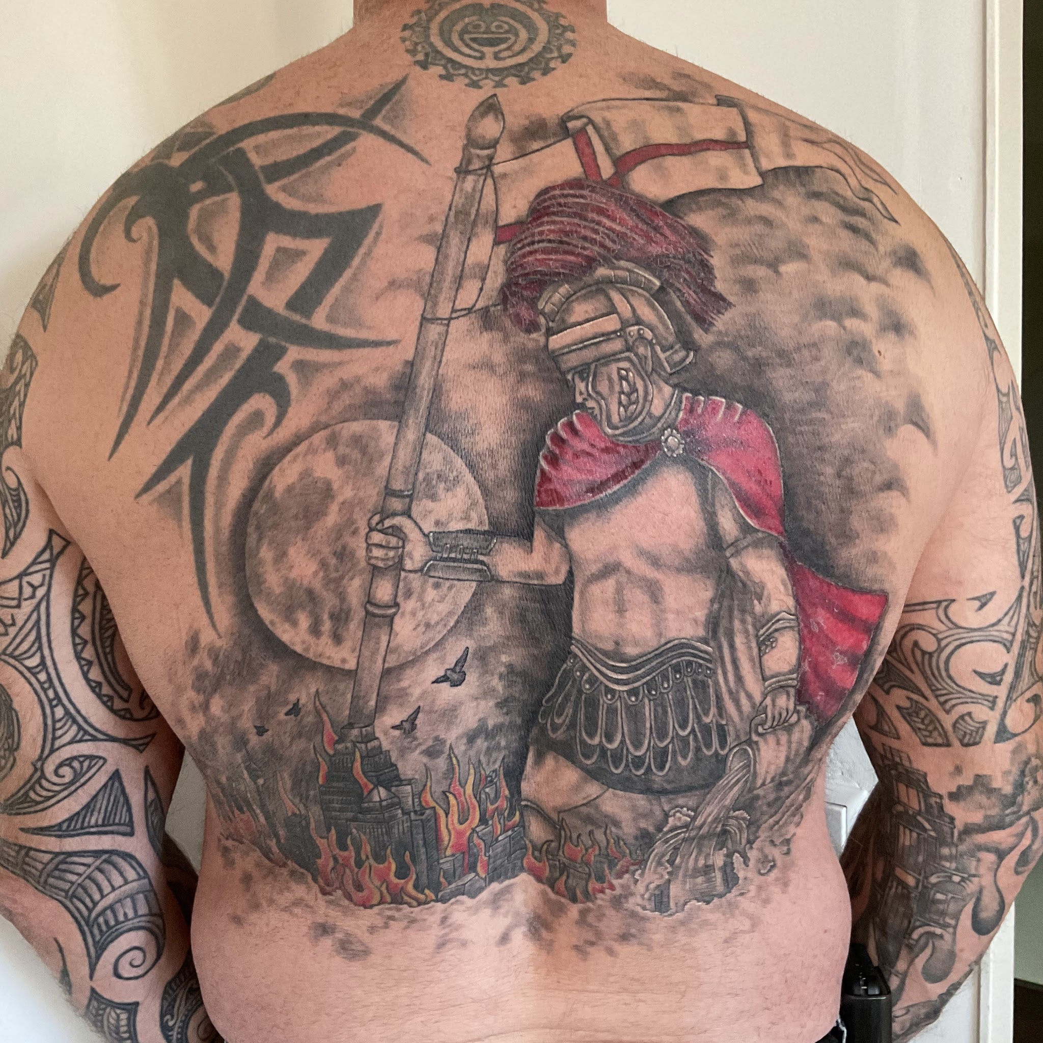 Grote zwart-grijze tattoo van een gladiator met rode cape over de hele rug