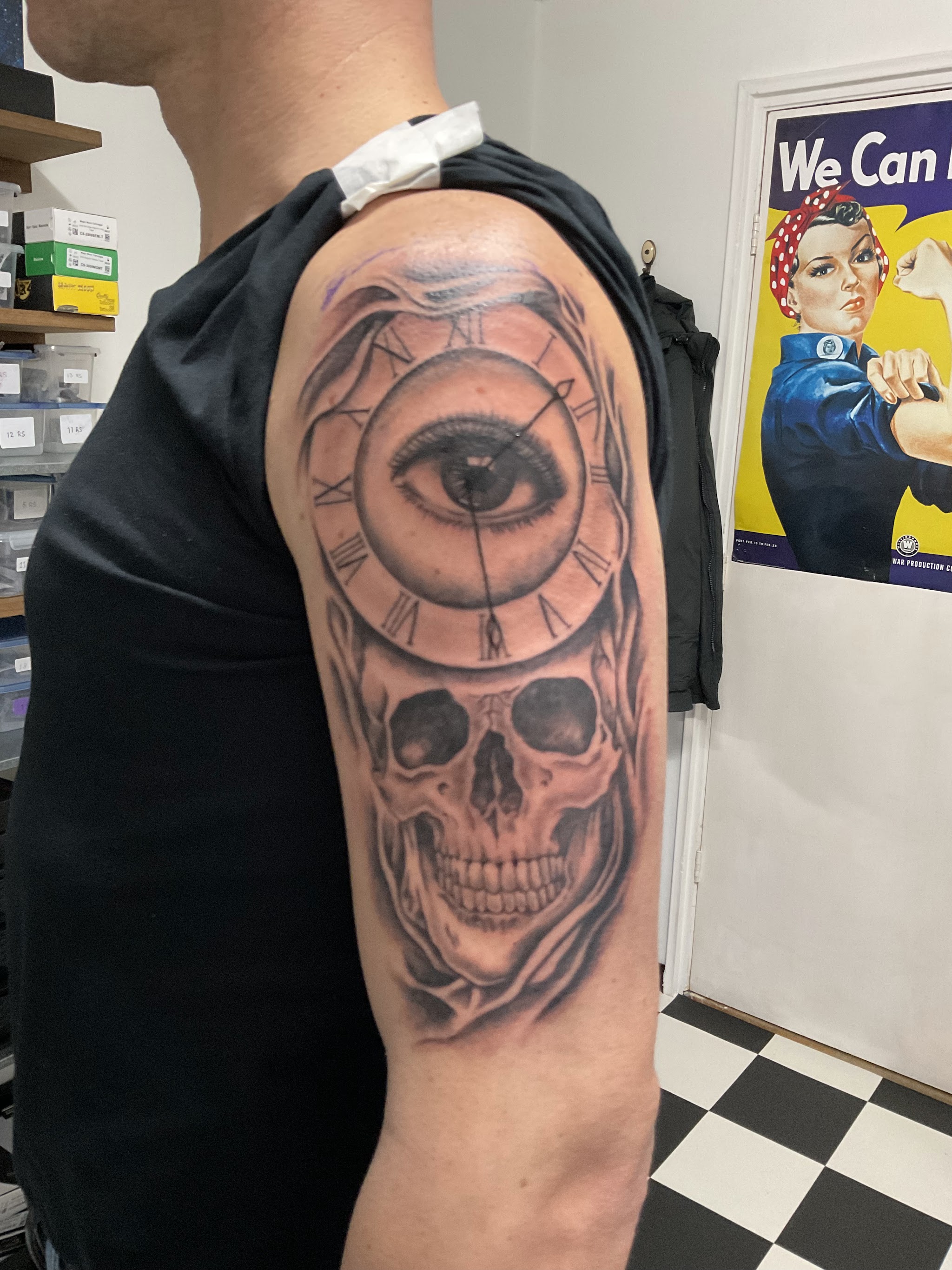Tattoo van een oog, een klok en een schedel op de bovenarm